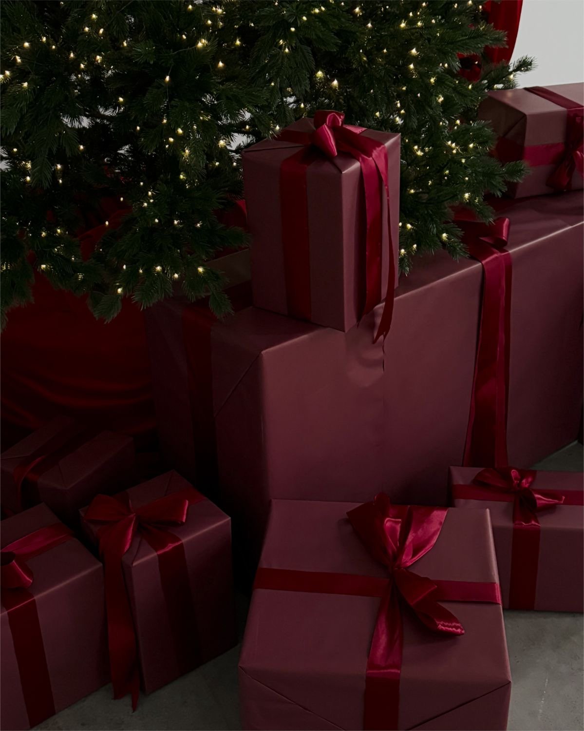 White gift boxes tied with pink ribbon beside a bunch of dried roses