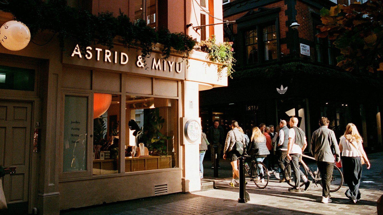 A London shopping street in the late afternoon, people walking past shopfronts