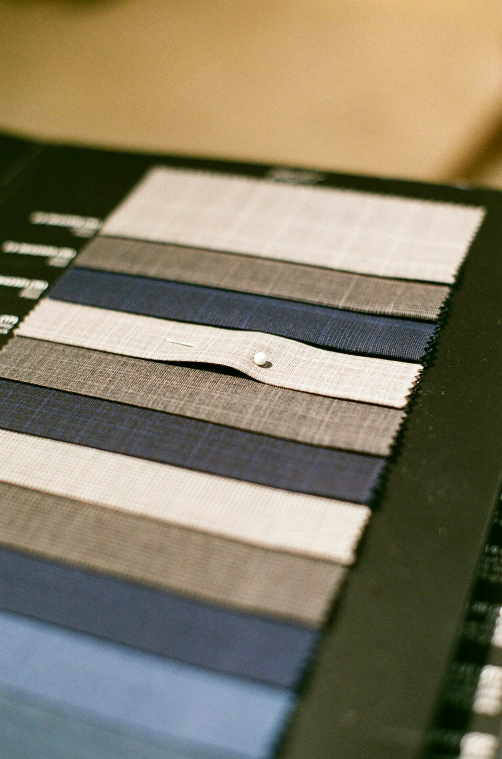 A tailor's book of wool swatches open on a table